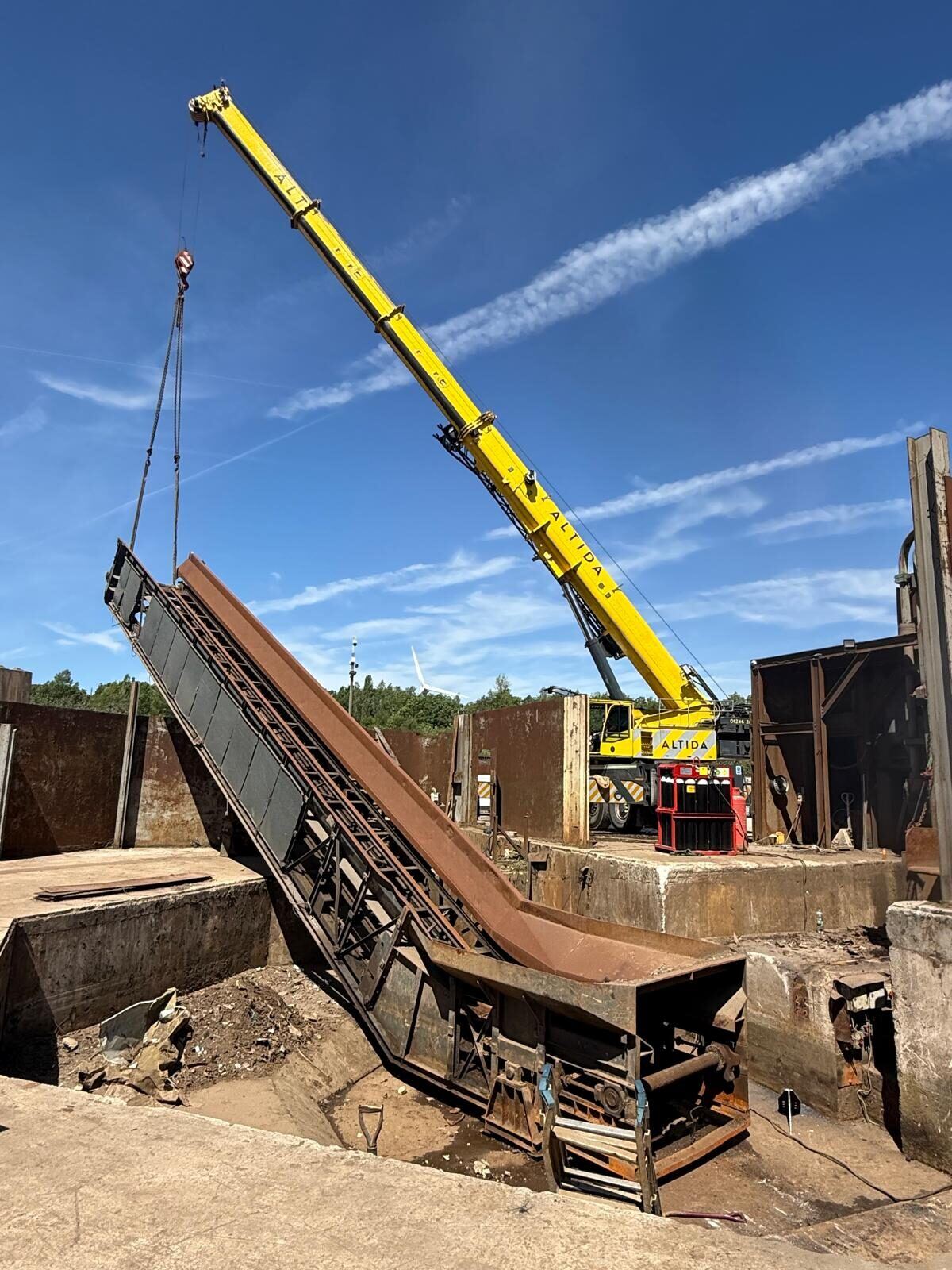 A section of recycling plant lifted clear of the pit on chains at the recycling site