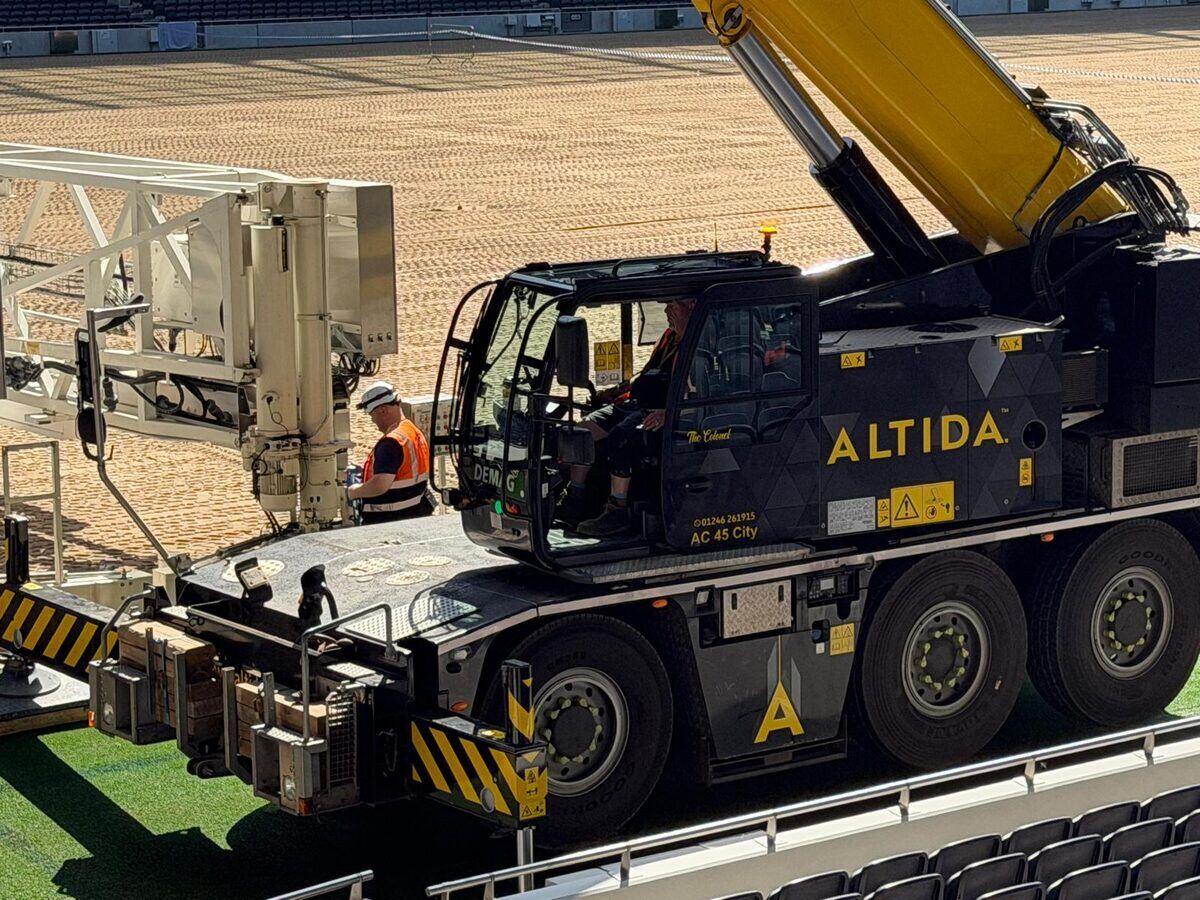 Altida's Demag AC 45 City compact crane set up on the pitch, boom raised in the stadium
